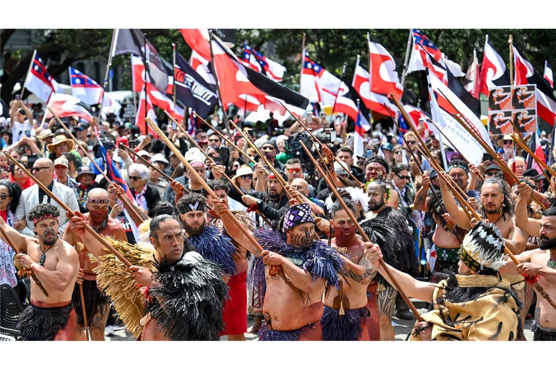 Zehntausende bei Maori-Protesten in Neuseeland Demonstranten tragen die traditionelle Kleidung der indigenen Bevölkerung und präsentieren die Maori-Flagge,