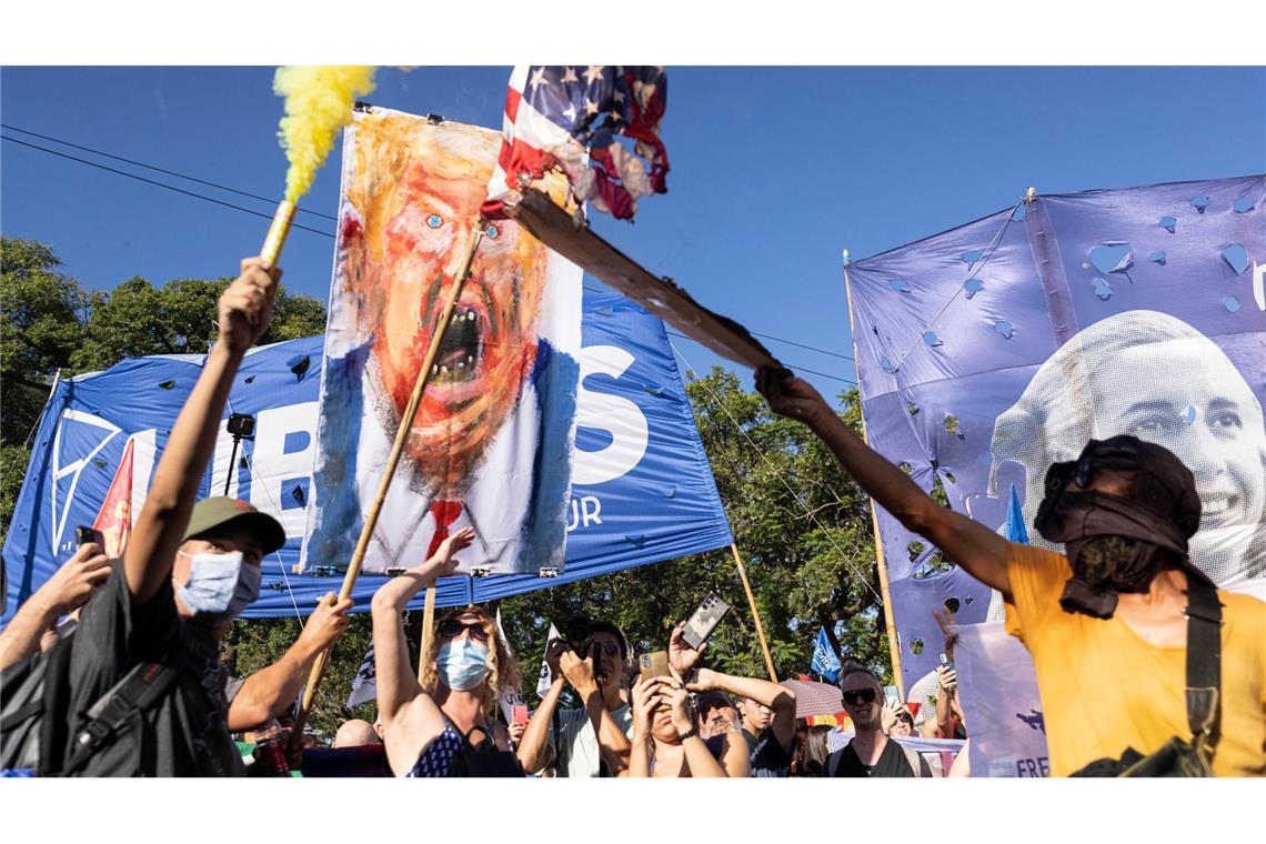 Demonstranten zünden mit einer Fackel eine amerikanische Fahne an.