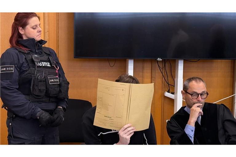 Der Angeklagte (M) verdeckt sein Gesicht vor dem Urteil im Prozess um den Tod eines zwölfjährigen Jungen auf einem Supermarktparkplatz in Niedernhall, rechts sein Anwalt Andreas Kugel (Archivfoto).