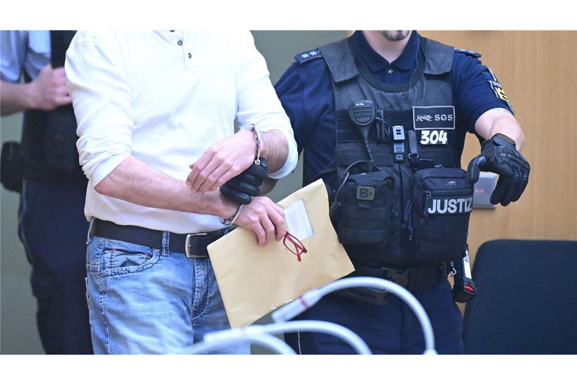 „Sonst blase ich euch das Licht aus!“ Der Anklagte Marco van H. wird am 29. April 2024 von Justizwachtmeister in den Gerichtssaal geführt. Die neun Angeklagten sind duch Glasscheiben von ihren Anwälten und Zuschauern getrennt. Mit ihren Verteidigern sprechen sie über eine eigene Kommunikationsanlage.