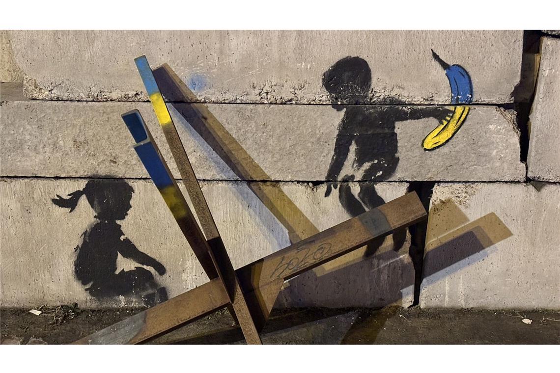 Kaffee, Tee und Wut auf Trump Der anonyme Streetartkünstler Banksy hat auf eine Straßensperre am Maidan zwei Kinder gesprüht, die eine Panzersperre zweckentfremden und darauf wippen. Insgesamt hat der Künstler in Kiew und den Vorten Borodjynka und Irpin fünf Kunstwerke gegen den russischen Angriff und für Frieden geschaffen.