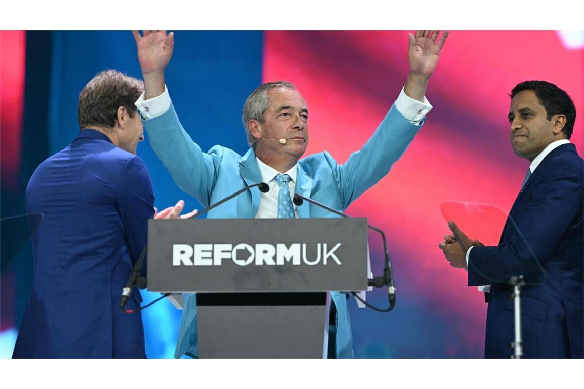 Der Chef der Reform UK Partei, Nigel Farage, wird nach seiner Rede auf dem Parteitag in Birmingham gefeiert. Auf der Bühne spenden ihm der stellvertretende Vorsitzende Richard Tice (L) und der Schatten-Innenminister Zia Yusuf Beifall.