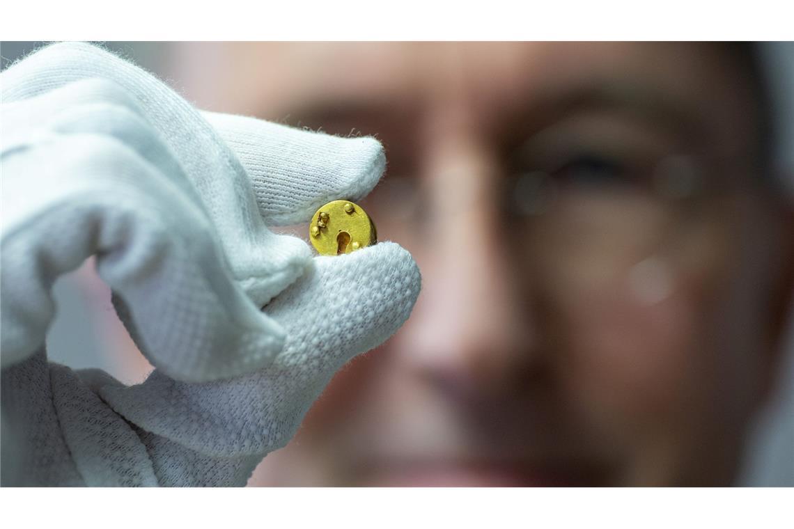 Römisches Mini-Dosenschloss aus Gold gibt Rätsel auf Der Chefarchäologe des LWL, Michael Rind, hält das Minischloss zwischen Daumen und Zeigefinger.