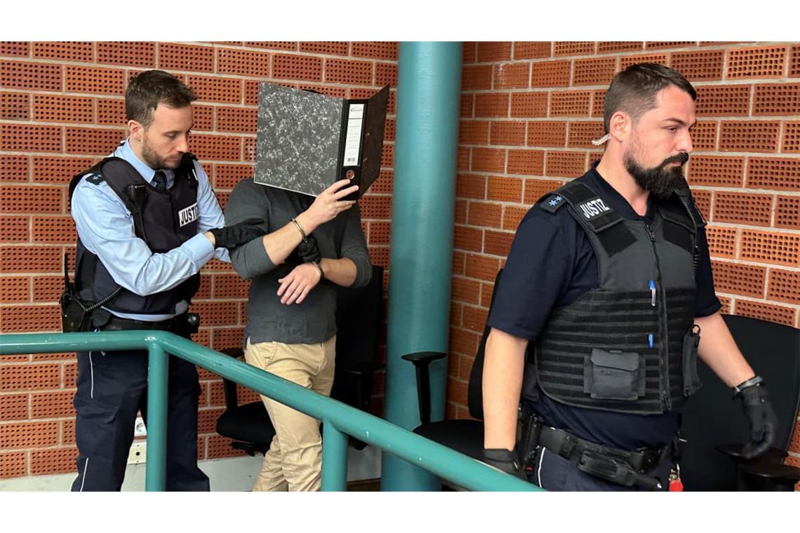 Der falsche Schönheitsarzt wird in Konstanz vor den Richter geführt. Sein Gesicht versteckt er vor den Kameras der Journalisten hinter einem Aktenordner. 