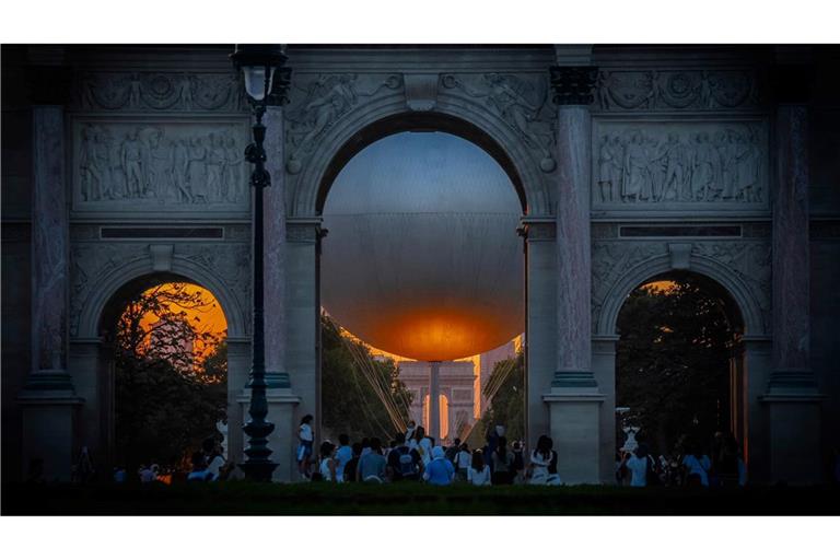 Der Heliumballon, der während der Olympischen Spiele 2024 verwendet wurde, und der Arc de Triumph sind bei Sonnenuntergang in Paris sehen.