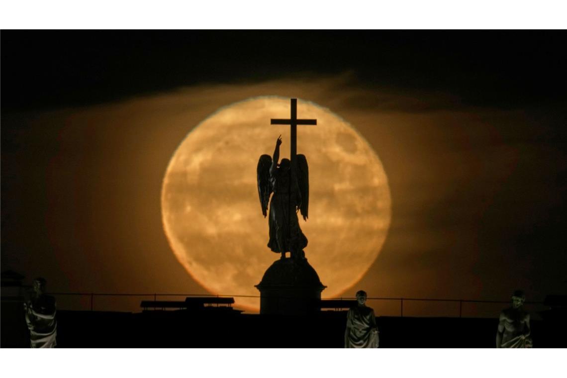 Der Mond geht hinter einer Engelsstatue auf der Alexandersäule auf dem Palastplatz über St. Petersburg auf.