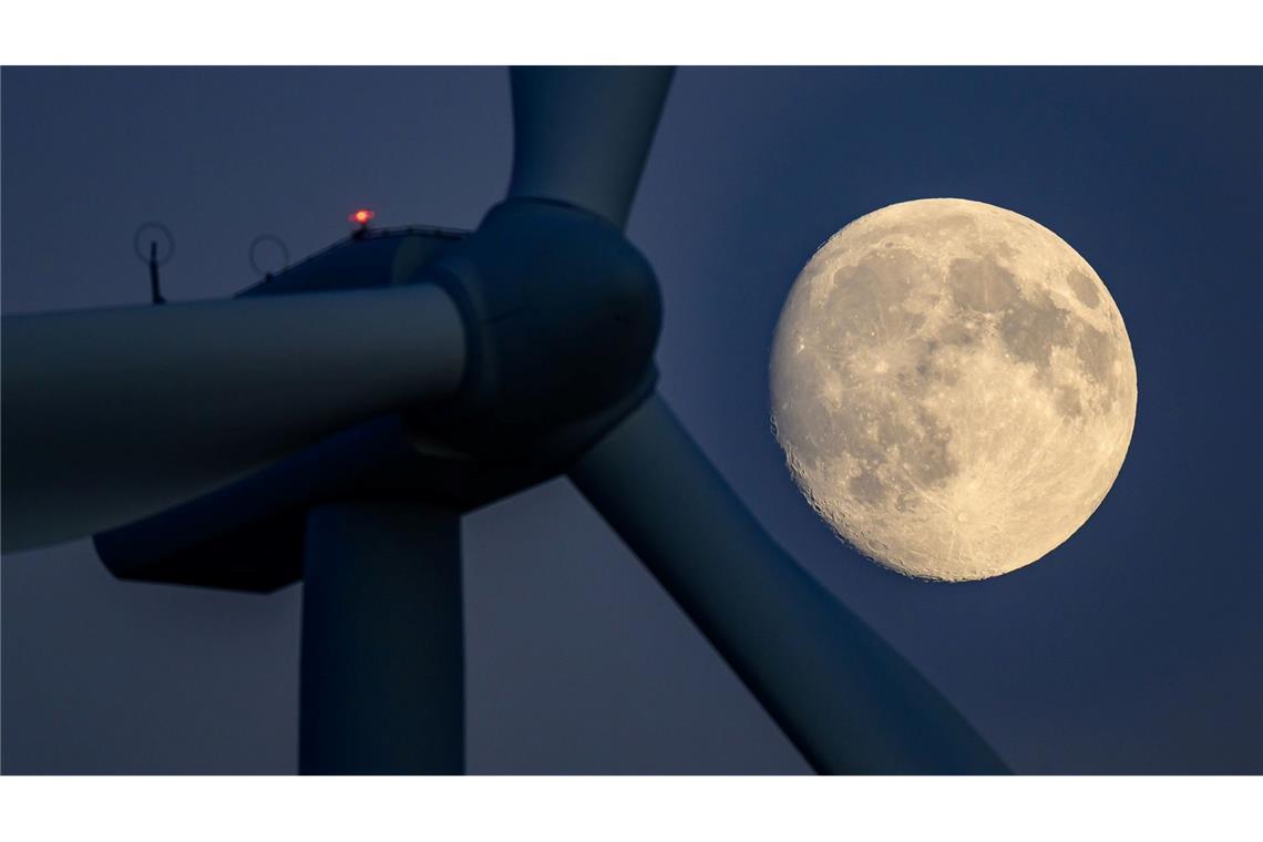 Der Mond ist hinter einer Windenergieanlage in Brandenburg zu sehen.