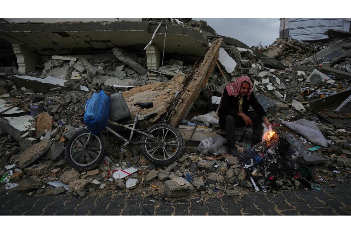 Der Palästinenser Mohammed al-Jabri, 58, wärmt sich neben einem Feuer, während er auf den Trümmern eines Gebäudes sitzt, das während der israelischen Luft- und Bodenoperationen im Viertel Sheikh Radwan zerstört wurden.