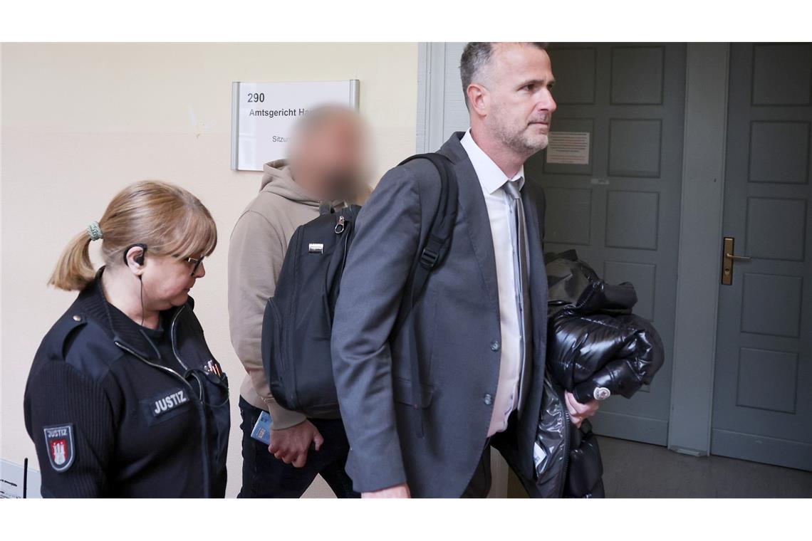 Der Zeuge (Mitte des Bildes) wird von seinem Anwalt (rechts im Bild) in den Gerichtssaal begleitet.