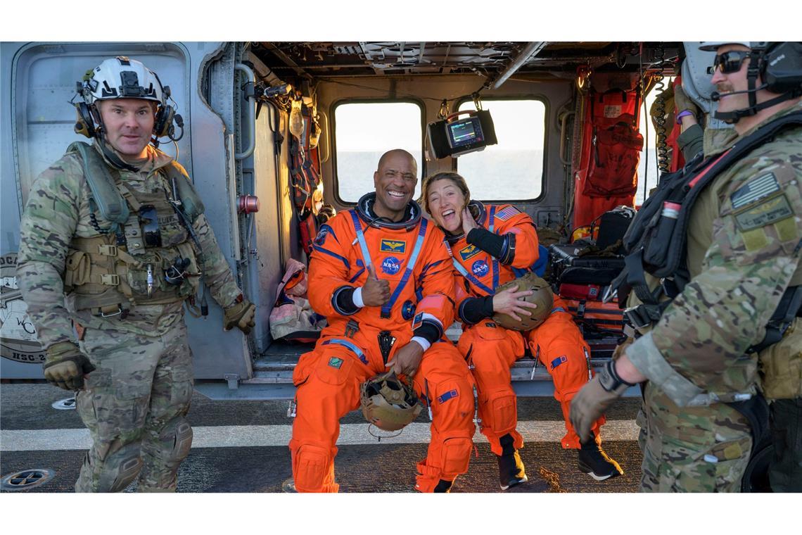 Die Astronauten Victor Glover und Christina Koch sitzen auf einem Hubschrauber der Navy auf dem Flugdeck des Schiffs USS John P. Murtha, nachdem sie aus ihrem "Orion"-Raumschiff geholt wurden.