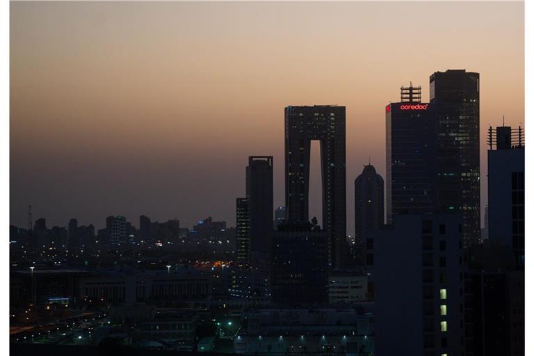 Die aufgehende Sonne färbt den Himmel hinter der Skyline von Kuwait-City rötlich.