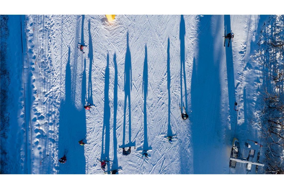 Bilder des Tages Die Aufnahme einer Fotodrohne zeigt aus ungewohnter Perspektive, wie Wintersportler im Skigebiet Erlebnisberg Altenberg neben einem Skilift die Piste hinunterfahren.