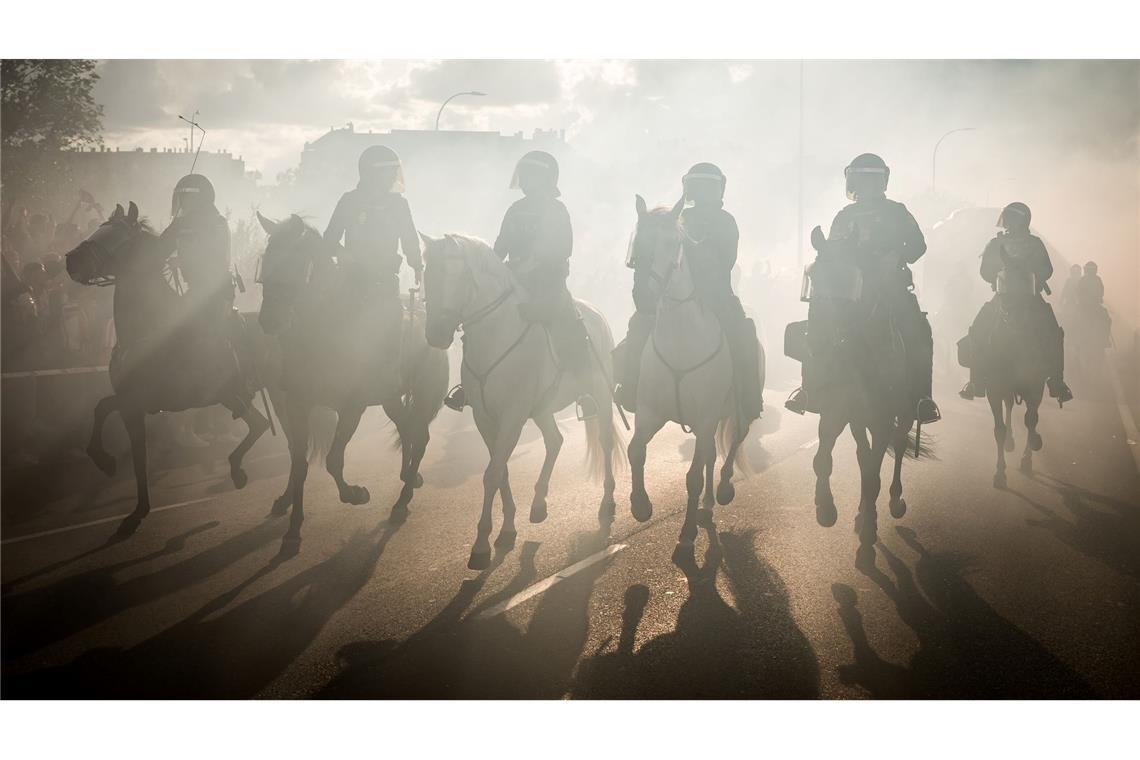Die berittene Polizei reitet im Rauch während der Einsätze im Vorfeld des Spiels Atlético Madrid gegen FC Arsenal in der Champions League.