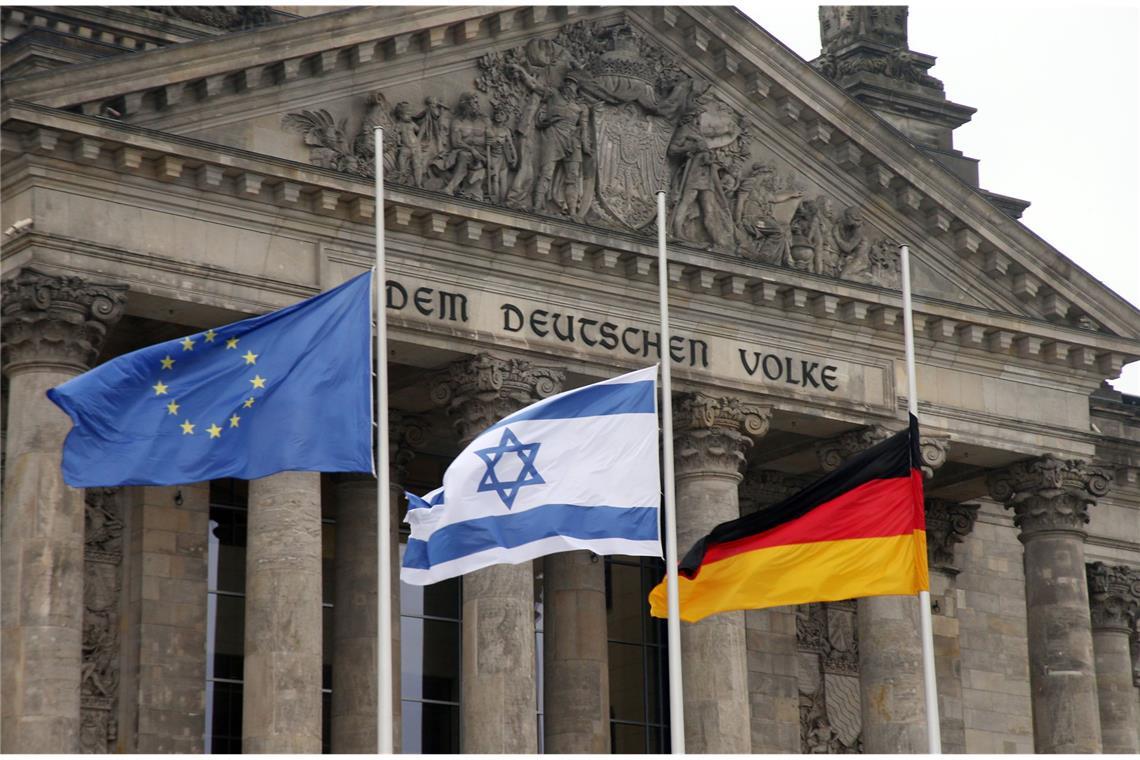 Warum wehen die Flaggen heute auf halbmast? Die europäische, die israelische und die deutsche Flagge auf halbmast vor dem Reichstag in Berlin.