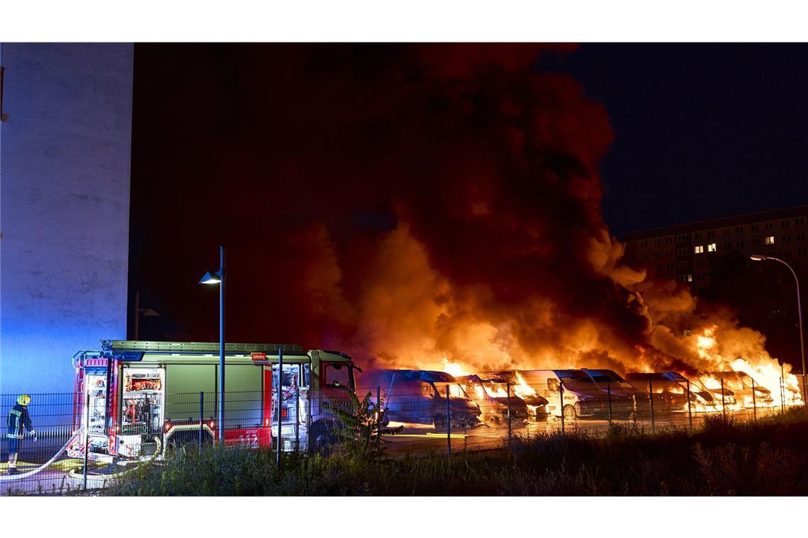 Die Feuerwehr versucht nach einem mutmaßlichen Brandanschlag in Berlin-Lichtenberg brennende Kleintransporter zu löschen.