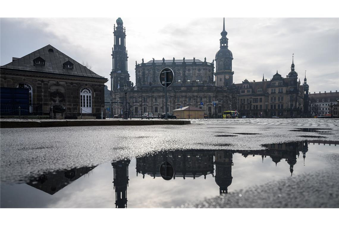 Bilder des Tages Die Hofkirche (l) und der Hausmannsturm spiegeln sich in der Altstadt auf dem Theaterplatz in einer Pfütze.
