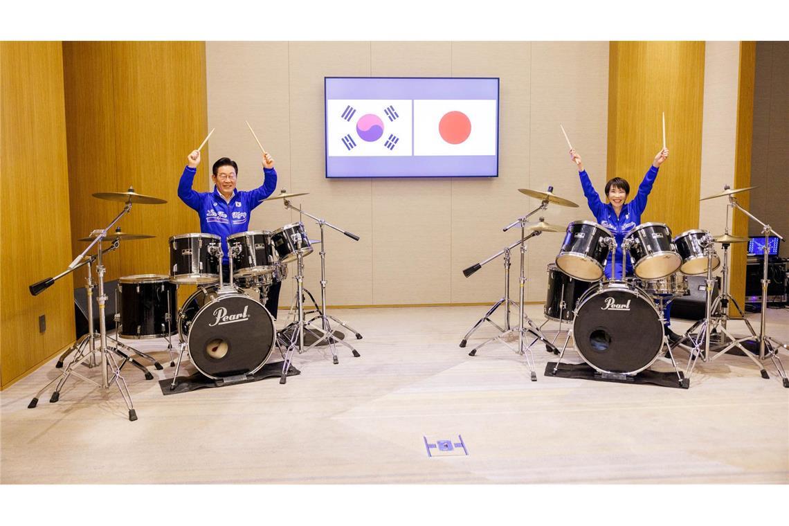 Die japanische Ministerpräsidentin Sanae Takaichi (r) und der südkoreanische Präsident Lee Jae Myung spielen Schlagzeug.