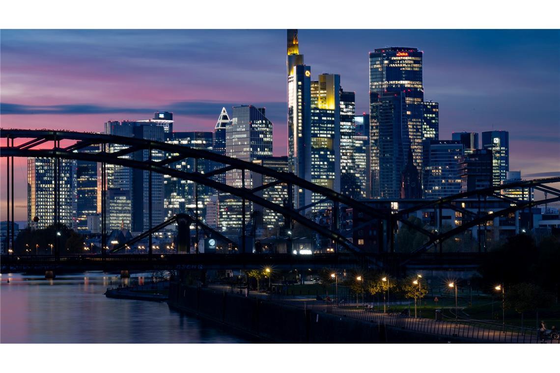 Die Lichter der Bankenskyline von Frankfurt leuchten in der Abendstimmung.