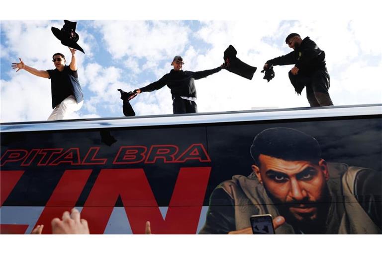 Die Rapper Lacazette, Capital Bra und Samra werfen bei einer Fanaktion in Kreuzberg T-Shirts von einem Tourbus.