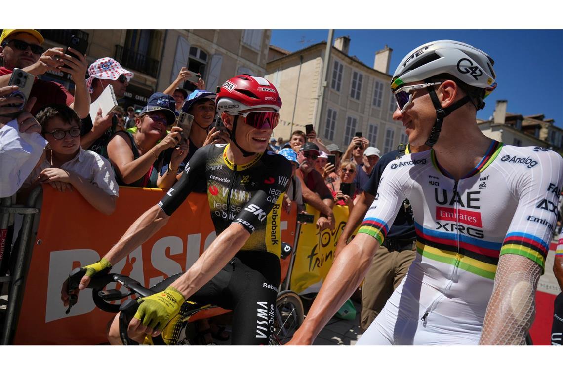 Die Rivalen Jonas Vingegaard (l) und der Slowene Tadej Pogacar (r) unterhalten sich vor dem Start.