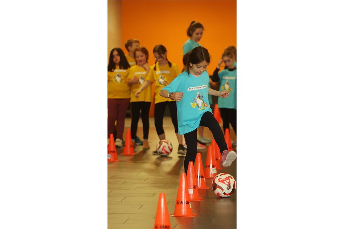 Die Schlangen-Station: mit einem Fußball dribbeln die Kinder im Slalom durch die Hütchen.