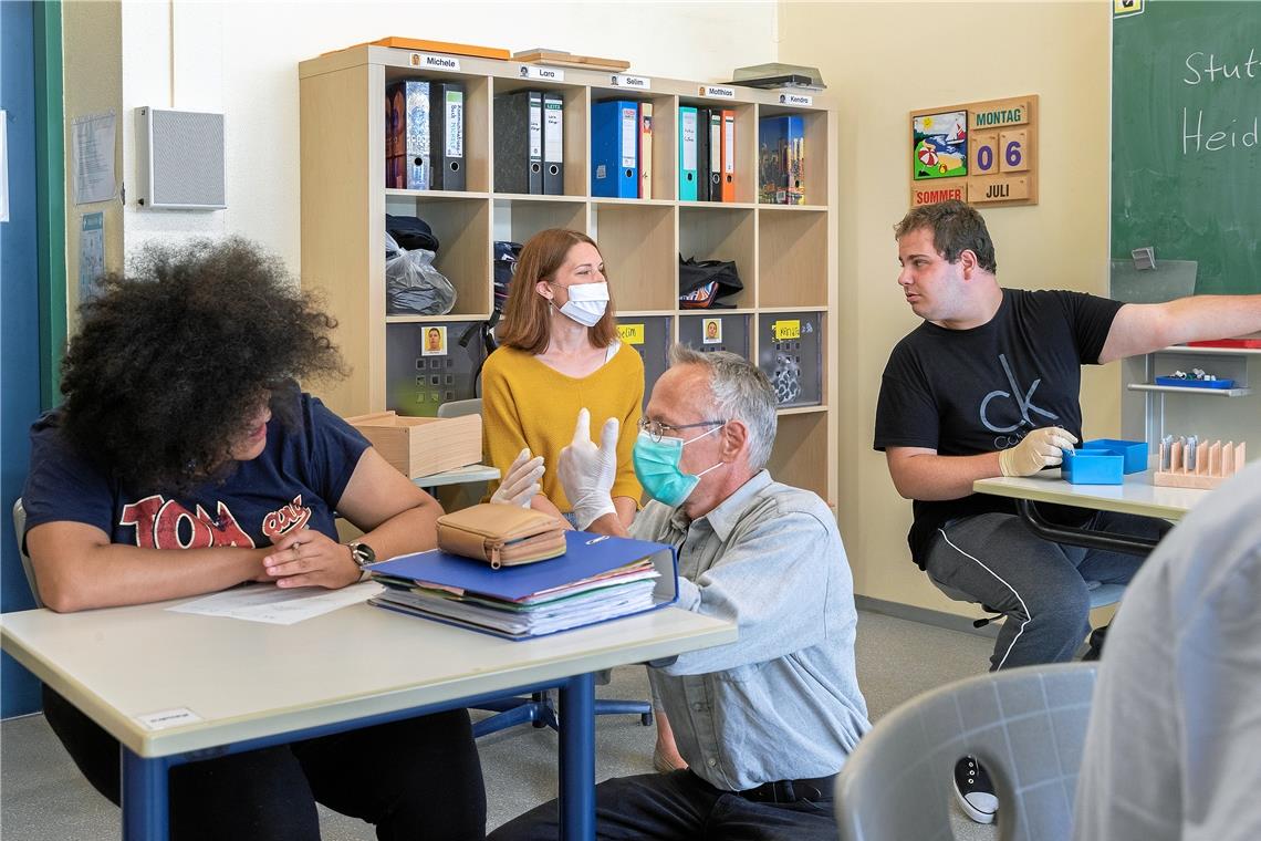 Die Schüler der Berufsschulstufe können wieder täglich in den Unterricht kommen: Kendra (links) und Michele (rechts) werden von der pädagogischen Assistentin Katja Bergner (hinten) und ihrem Klassenlehrer Peter Müller (vorne) in einer kleinen Gruppe – vier statt sechs Jugendliche und junge Erwachsene – betreut. Foto: J. Fiedler