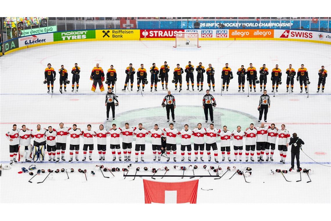 Die Schweizer (unten) und das deutsche Team steht auf dem Eis.