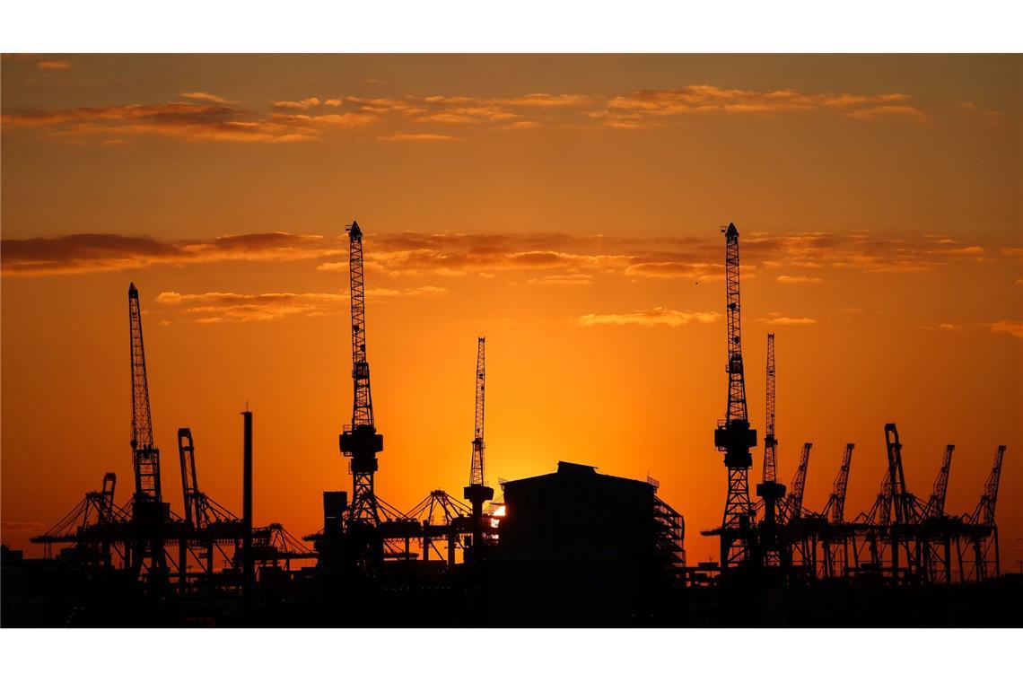 Bilder des Tages Die Sonne geht hinter Containerbrücken und Hafenkränen im Hamburger Hafen unter.