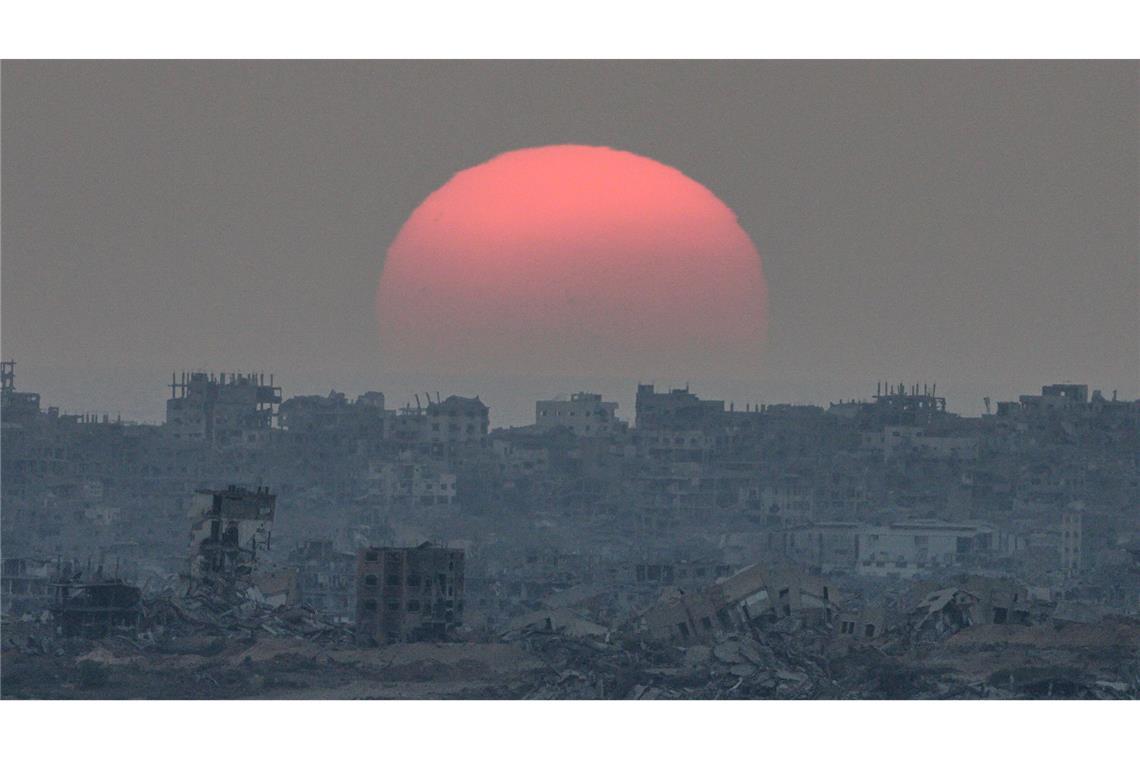 Bilder des Tages Die Sonne geht hinter Gebäuden unter, die bei israelischen Boden- und Luftangriffen im Gazastreifen zerstört wurden, gesehen vom Süden Israels aus.