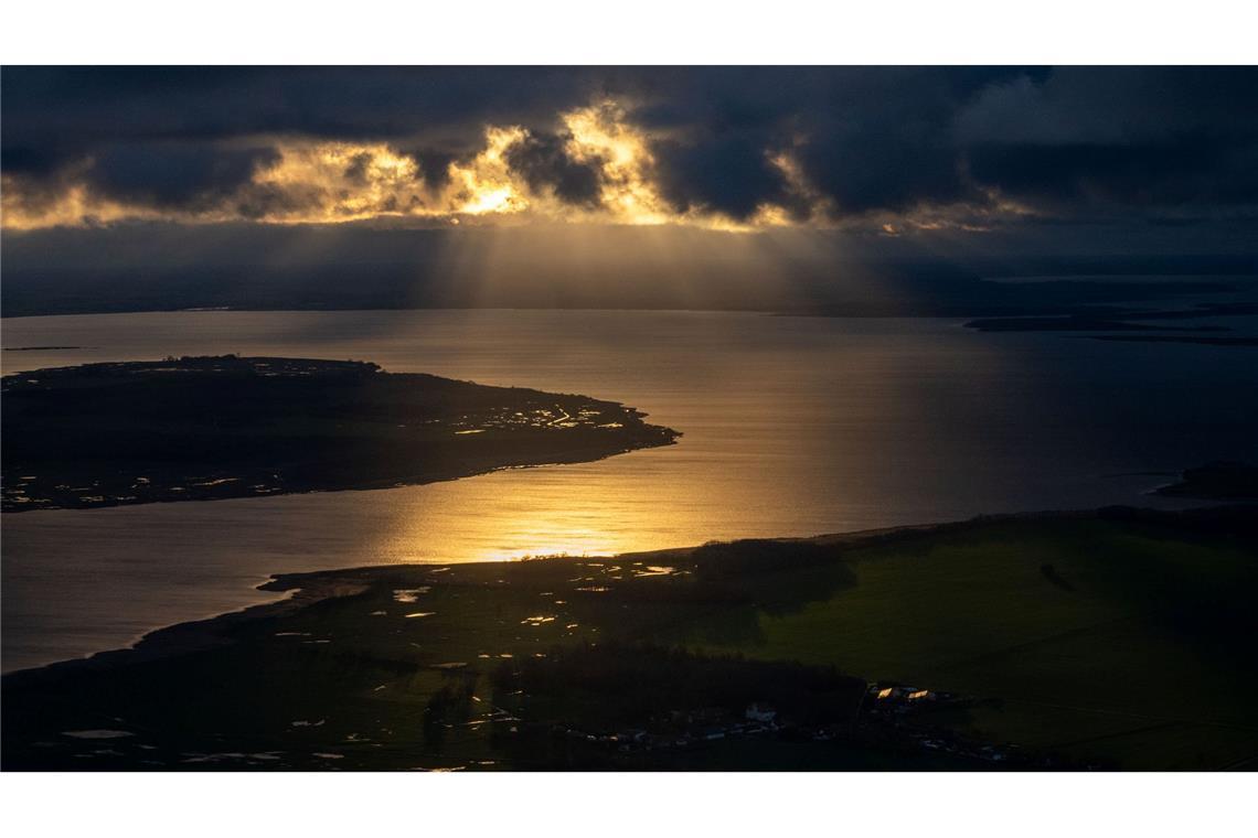Bilder des Tages Die Sonne geht hinter Wolken über der Insel Rügen unter.