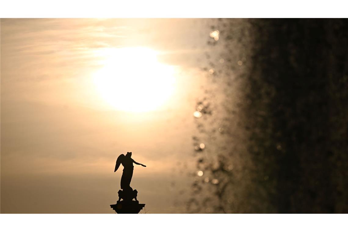 Bilder des Tages Die Sonne geht vor der Jubiläumssäule auf dem Schlossplatz unter, rechts die Fontäne eines Wasserspiels.