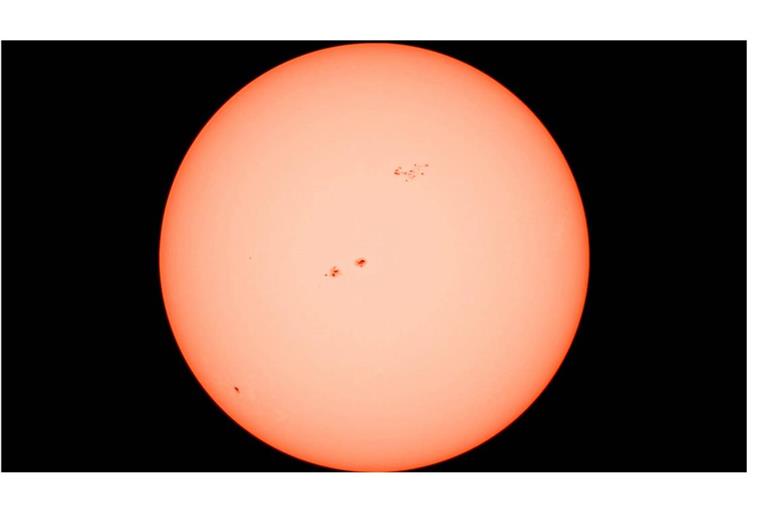 Die Sonne in all ihrer Kraft aufgenommen durch ein Teleskop mit Sonnenfilter. Deutlich sichtbar: mehrere Sonnenflecken auf der glühenden Oberfläche, die eindrucksvoll die Dynamik und Aktivität unseres Sterns zeigen.