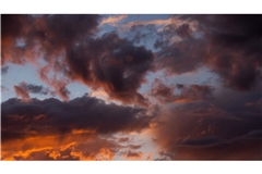 Die untergehende Sonne lässt die Wolken über Köln rötlich schimmern.