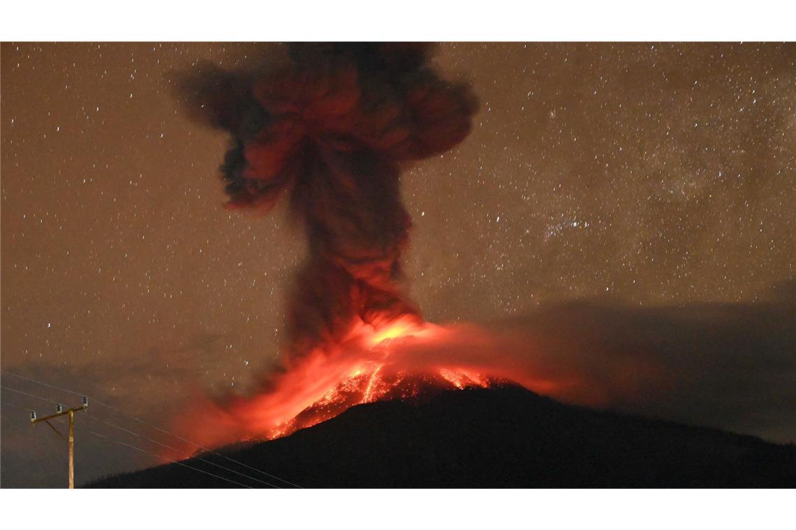 Auf der Urlaubsinsel Flores speit ein Vulkan Rauch und Asche Dieses Bild zeigt den Kegel am Vulkan Lewotobi Laki-Laki. Bei dem Ausbruch steigt eine hohe Aschewolke in den Himmel und glühende Lava rinnt die Hänge hinunter.