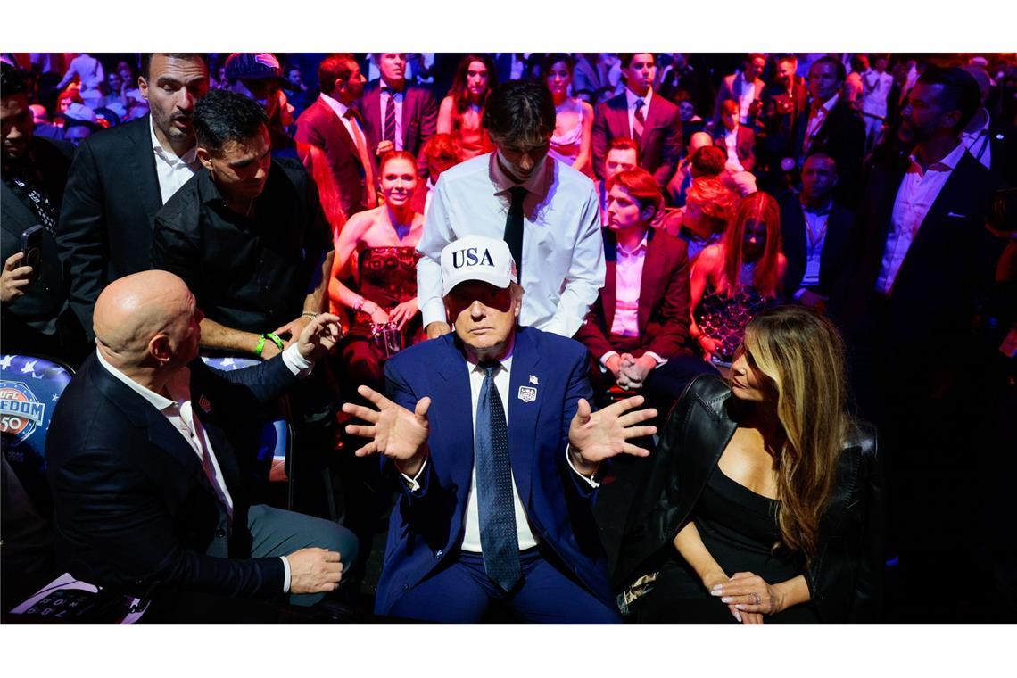 Donald Trump gestikuliert umgeben von UFC-Präsident und CEO Dana White (links) und First Lady Melania Trump.
