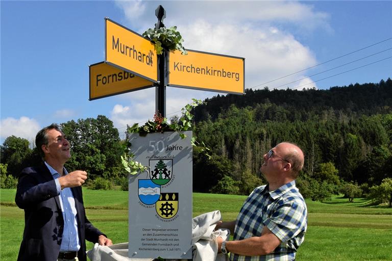 Dort, wo Murrhardt und die ehemals selbstständigen Gemeinden Fornsbach und Kirchenkirnberg zusammentreffen, erinnert nun ein Wegweiser an den Zusammenschluss und gemeinsamen Weg seit 50 Jahren. Die Aufnahme zeigt Landrat Richard Sigel (links) und Bürgermeister Armin Mößner bei der Enthüllung. Foto: E. Klaper