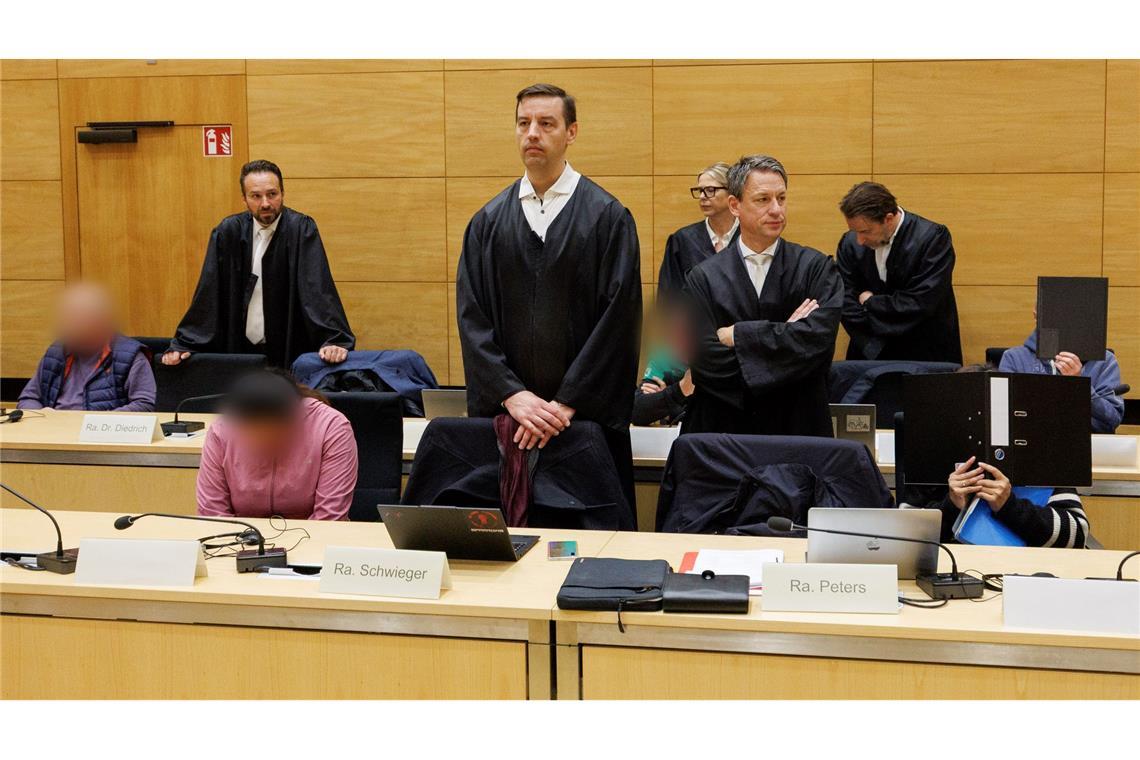Drei der zehn Angeklagten sitzen am ersten Prozesstag im Landgericht Bielefeld neben ihren Verteidigern.