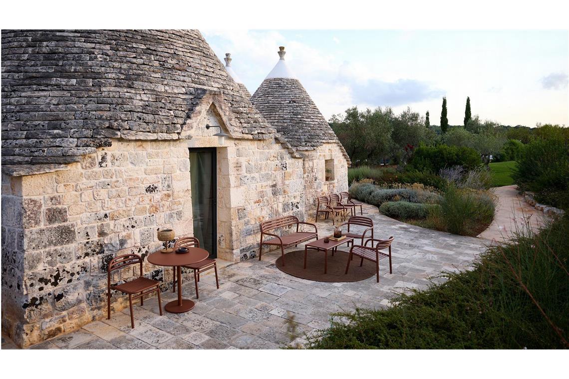 Ebenfalls horizontale Linien und dazu noch dunklerem Rot –  „Wüstenrot“, ein ins Braun tendierendes Dunkelrot, die minimalistisch daherkommende Serie „Bliss“ von Foersom & Hiort-Lorenzen MDD  besteht aus Stühlen, Tisch und Loungesofa – hier aus pulverbeschichtetem Aluminium, auch natürliches Rattan ist im Programm.