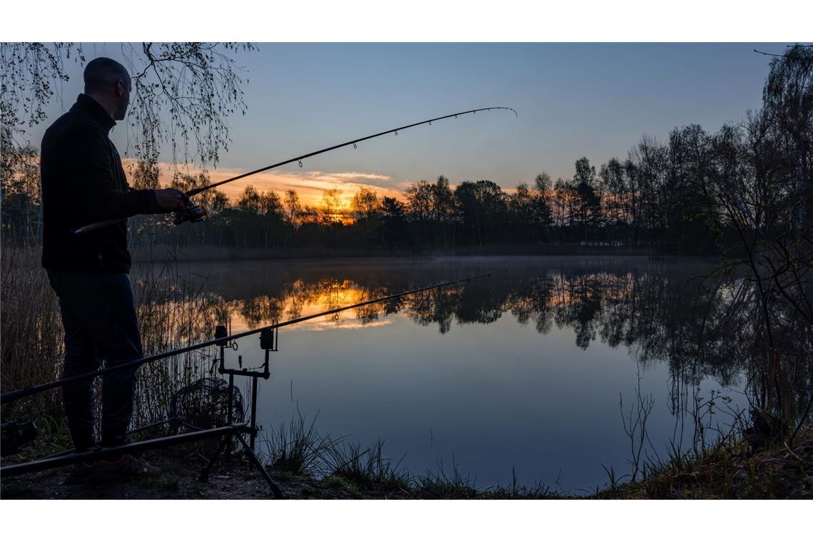 Bilder des Tages Ein Angler steht bei Sonnenaufgang an einem Teich in Brandenburg.
