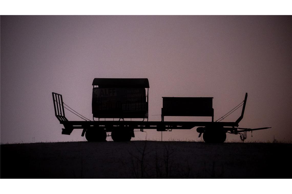 Ein Anhänger steht auf einer schneebedeckten Wiese bei Bitburg und wird von Straßenleuchten erhellt.