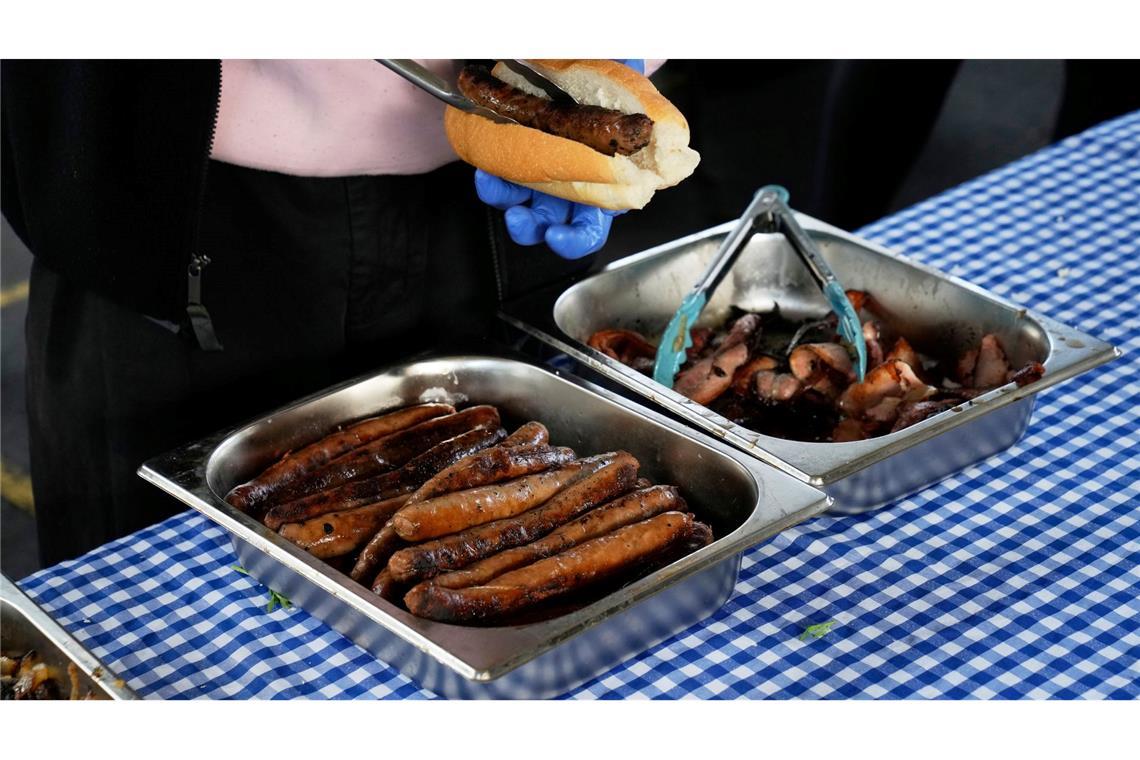 Bilder des Tages Ein Arbeiter bereitet in der Marrickville Public School in Sydney, Australien, eine "Demokratie-Wurst" für jemanden zu, der bei den Parlamentswahlen seine Stimme abgegeben hat. Der verführerische Duft brutzelnder Würstchen ist in Australien fester Bestandteil jeder Wahl. Traditionell steht vor vielen Wahllokalen ein Grill, an dem sich die Bürger mit einer Art Hot Dog (Bratwurst im weichen Brötchen mit Zwiebeln, Senf und Ketchup) stärken können: dem sogenannten "Democracy Sausage".