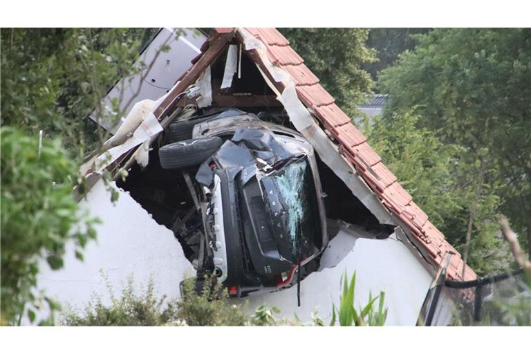 Ein Auto liegt nach einem kurzen Flug seitlich in der Mauer einer Scheune.