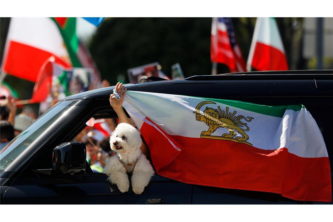 Ein Autofahrer befestigt eine iranische Flagge an einem Fenster.