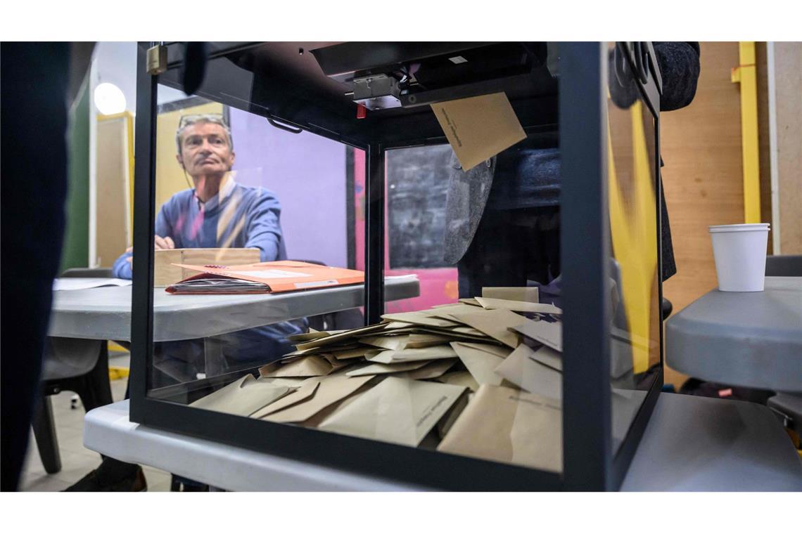 Ein Beamter beobachtet, wie Wähler während der ersten Runde der französischen Kommunalwahlen 2026 in Perpignan, Südfrankreich, ihre Stimme abgeben.