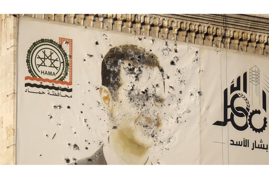 „Der Gedanke, nicht mehr Flüchtling zu sein auf der Welt, ist sehr, sehr groß“ Ein Bild des syrischen Präsidenten Baschar al-Assad in der Stadt Hama, durchlöchert von Kugeln.