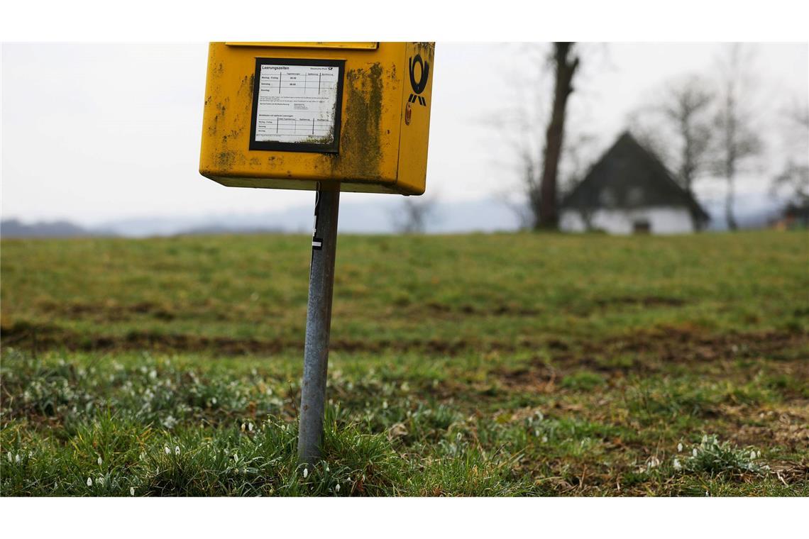 Zahl der Post-Beschwerden steigt Ein Briefkasten der Deutschen Post steht auf einer Wiese am Rand einer Siedlung im Bergischen Land (NRW).