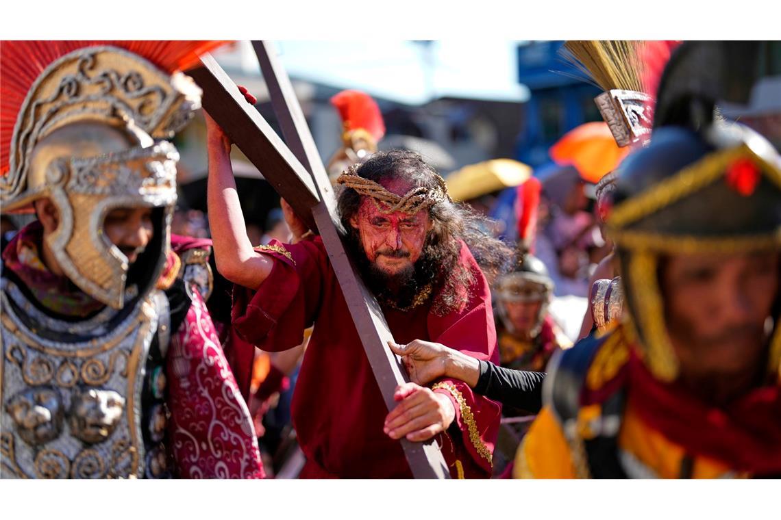 Bilder des Tages Ein Darsteller, der die Rolle von Jesus Christus spielt, trägt ein Holzkreuz während einer Prozession, die seine Passion und seine Leiden nachstellen.