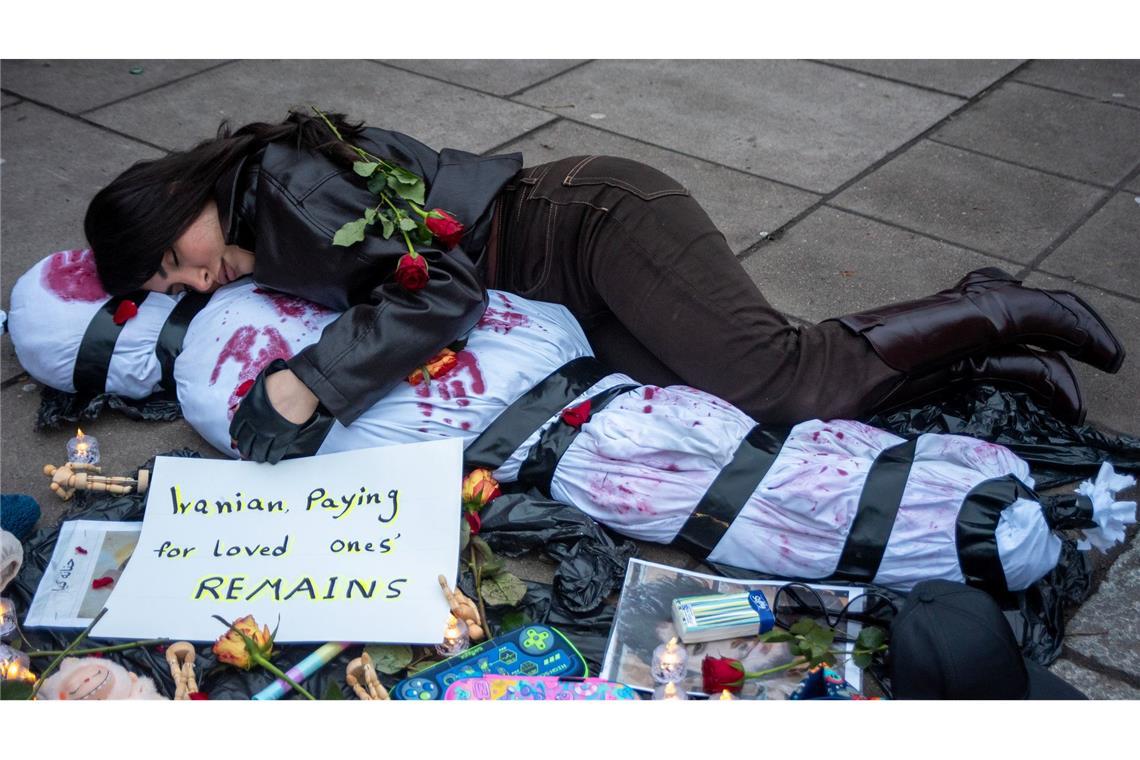 Ein Demonstrant liegt mit einem menschlichen Leichnam, der ein Opfer symbolisiert, auf dem Boden.