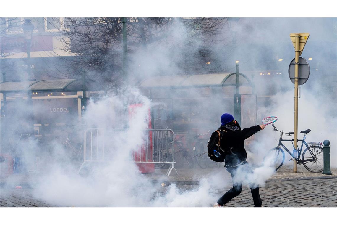 Ein Demonstrant schlägt bei den Protesten in Brüssel gegen einen Tränengasbehälter.