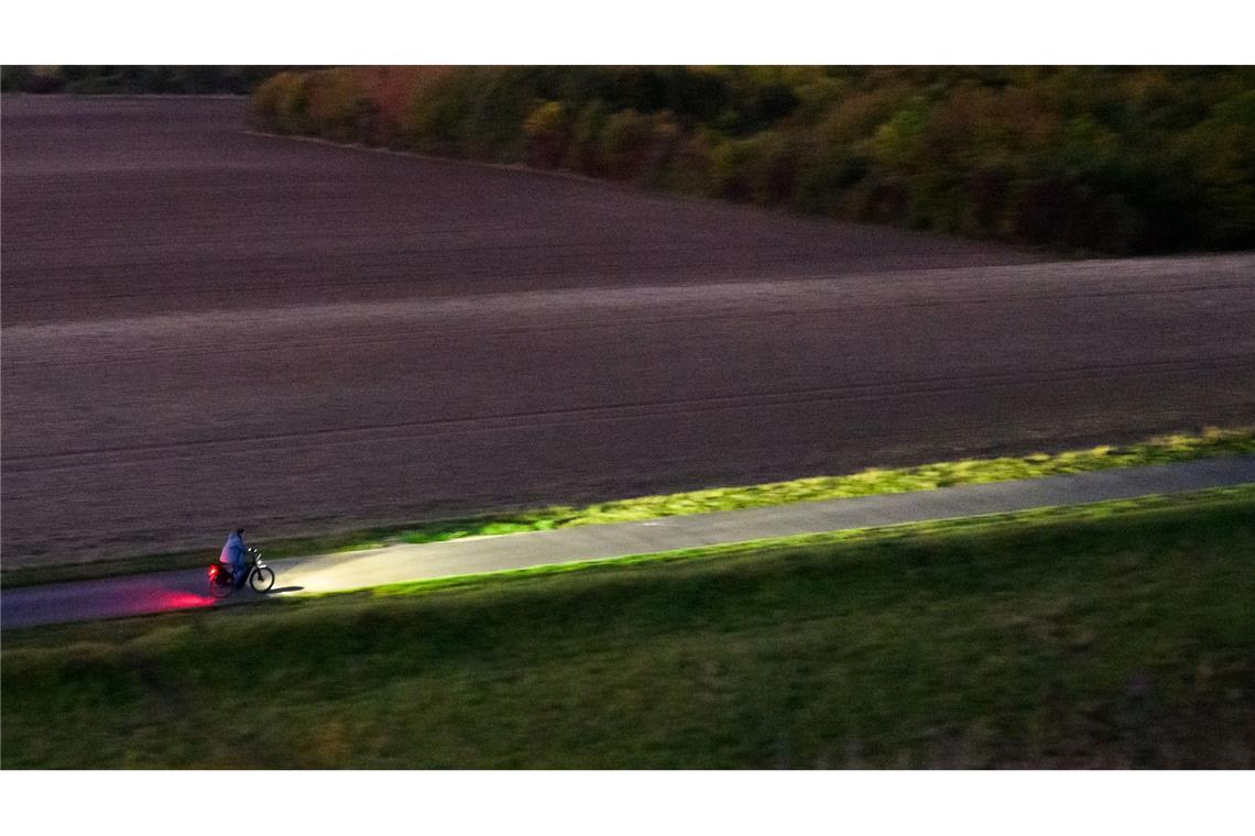 Bilder des Tages Ein Fahrradfahrer fährt am frühen Morgen mit Licht über einen Feldweg bei Hannover.